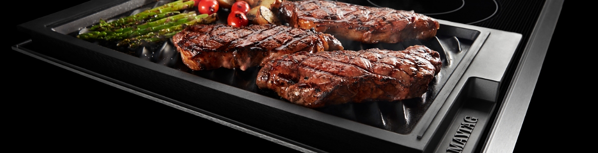 Steak and other grilled items are seen on a stovetop